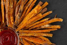 baked sweet potato fries with ketchup and mustard on a black surface top view from above