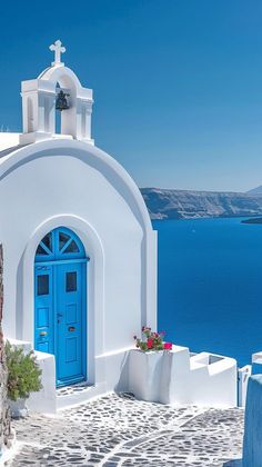 a blue door is on the side of a white building with a cross above it