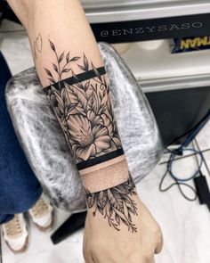 a woman's arm with flowers on it and a black ribbon around the wrist