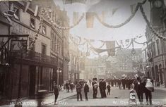 an old black and white photo of people walking down the street