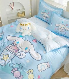 a bed with blue comforters and pillows on top of it next to a stuffed animal