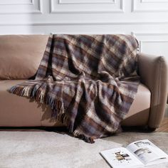 a couch with a blanket on top of it next to a book and coffee table