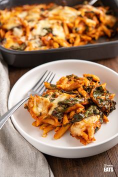 a white plate topped with lasagna next to a casserole dish on a wooden table