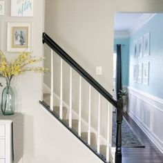 there is a vase with yellow flowers on the table next to the stairs in this house