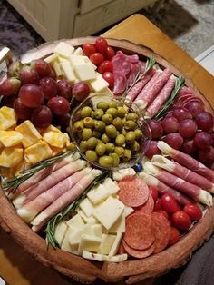 a wooden platter filled with different types of cheese and meats on top of a table