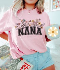 "Cute retro wildflower design for a new Nana. ♥ These Comfort Colors shirts are made of premium quality, soft heavyweight 100% ringspun cotton material that gets even softer with every wash. They have a loose boyfriend tee type fit and feel like your favorite tee that you've loved forever. Size up for a more oversized fit. ♥ Our shirts are printed using a high-end DTG (Direct to Garment) printer that uses water-based inks which are absorbed into the fabric, creating a smooth finish on the shirt, that won't fade or peel off (no vinyl!). ♥ MADE TO ORDER - Please allow 2-6 business days for this item to be made and prepared for shipping. ♥ Go back to my shop: cuteling.etsy.com ♥ Ready to buy? Click the big green \"Add to cart\" button. ♥ Question? Click the small blue \"Contact\" link under m Groovy Grandma Shirt, Personalized Pink T-shirt For Mother's Day, Mother's Day Floral Print Relaxed Fit T-shirt, Mother's Day Floral Print Crew Neck T-shirt, Mother's Day Cotton Graphic Tee T-shirt, Nana Shirts, New Grandma, Boyfriend Tee, Flower Shirt