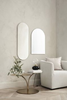 a living room with a couch, mirror and potted plant on the side table