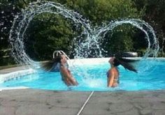 two girls are playing in the pool with water spouting from their heads and arms