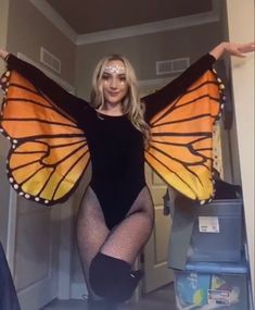 a woman in a black bodysuit holding a butterfly costume