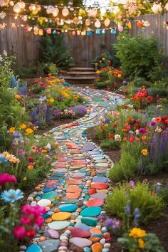 a garden path made out of stones with lights strung over the walkway and flowers growing on both sides