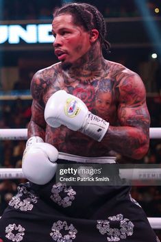 tattooed man in boxing ring with white gloves