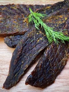 some kind of food that is on top of a wooden table with green sprigs