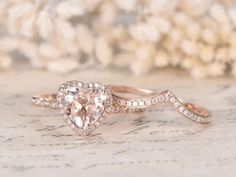 a pink diamond ring sitting on top of a piece of paper with flowers in the background