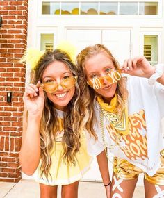 two girls are posing for the camera in front of a brick building wearing yellow and white clothing