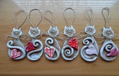 four ornaments with cats and hearts are hanging on a wooden table, ready to be decorated