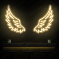 two yellow angel wings sitting on top of a table in front of a black wall