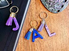 three keychains with letters and tassels on a table