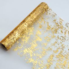 a roll of gold glitter paper sitting on top of a white surface