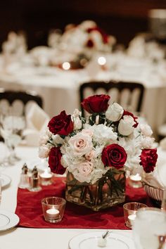 a vase filled with red and white flowers on top of a table covered in silverware