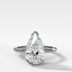 a pear shaped diamond engagement ring on a white background