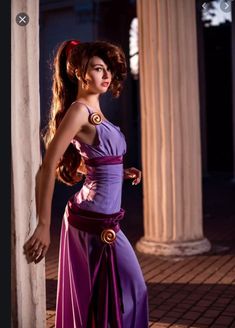 a woman in a purple dress standing next to columns