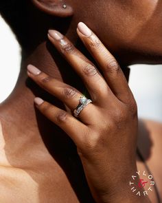 a close up of a person with their hand on her neck wearing a diamond ring