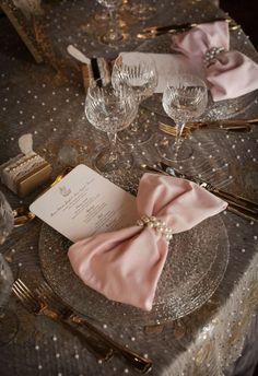 the table is set with pink napkins and place settings for an elegant dinner party