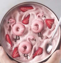 a bowl filled with strawberries and pink flamingos on top of ice cream next to a spoon