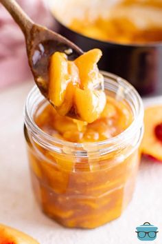 a spoon full of peach jam on top of a table