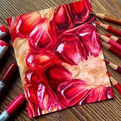 some crayons are laying on top of a piece of paper with red paint