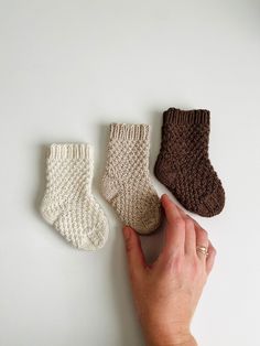 three pairs of knitted socks are shown in the shape of baby's feet