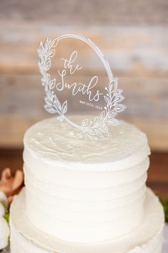 a white wedding cake with the name of the bride on top