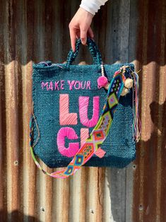 a hand holding a blue purse that says make your luu g on it with colorful beads and tassels