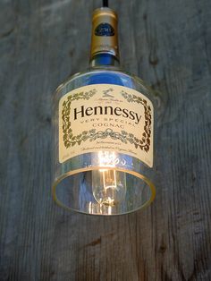 a bottle of hennessy gin is hanging from a light fixture on a wooden table