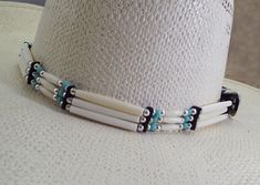 Be ready for compliments! This is a very UNIQUE Bone beaded hat band.  This  Cowboy hat band is very hard to miss.  2 colors beads with the white bone beads #1 has a light blue turquoise colored bead to add extra flare.  #2 has  black beads to compliment the White  bone beads.   Then it is trimmed with longer white bone beads and silver beads. The bead dividers are leather and the 3 piece silver buckle set is also attached with select supple leather.  It is uniquely DISTINCTIVE and very handsome Handmade White Headband Jewelry, White Handmade Jewelry Headband, Handmade White Jewelry Headband, Southwestern White Adjustable Hat, White Southwestern Adjustable Hat, Adjustable White Southwestern Hat, White Southwestern Hat Bands For The Beach, Traditional White Hat Bands For Rodeo, Traditional White Hat Bands For Festival