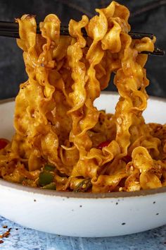 a bowl full of noodles with chopsticks sticking out of the top and some meat in the middle