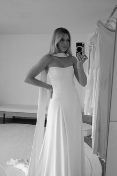 a woman in a white dress is taking a selfie with her camera and looking into the mirror