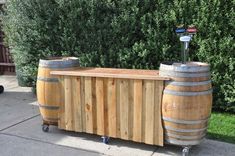 two wooden barrels sitting next to each other on top of a cement floor in front of some bushes