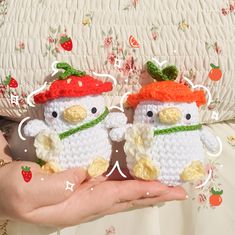 two small crocheted penguins are held in their hands