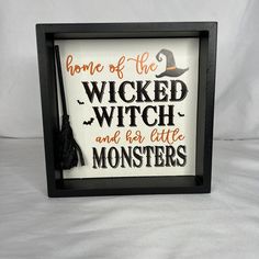 a black framed sign that says, home of the wicker witch and her little monsters