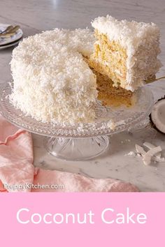 a coconut cake on a glass plate with a slice missing