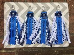 three blue and white ribbon keychains hanging on a brick wall