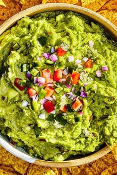 a bowl filled with guacamole surrounded by tortilla chips and salsa