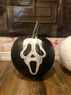 a black and white pumpkin with a ghost face painted on it