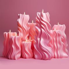 a group of pink candles sitting next to each other on top of a purple surface