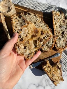 someone is holding up some bread with raisins on it next to a knife