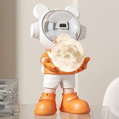 an orange and white toy holding a moon in it's hands on top of a table