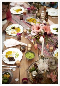 a group of people sitting at a table with plates and bowls on it, eating food