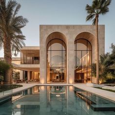 a large swimming pool in front of a building with arched windows and palm trees around it