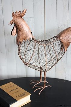 a metal chicken sculpture sitting on top of a table